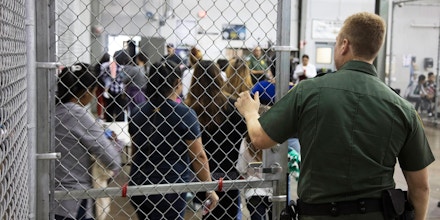 A U.S. Border Patrol agent watches as people who've been taken into custody.