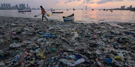 A man walks on plastic waste at a beach in Mumbai, India, on Nov. 8, 2019. 