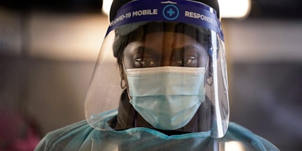 FILE - In this  Dec. 8, 2020, file photo, a health care worker wears personal protective equipment as she speaks to a patient at a mobile testing location for COVID-19 in Auburn, Maine. Doctors and nurses around the U.S. are becoming exhausted and demoralized as they struggle to cope with a record-breaking surge of COVID-19 patients that is swamping hospitals and prompting governors to clamp back down to contain the virus. (AP Photo/Robert F. Bukaty, File)