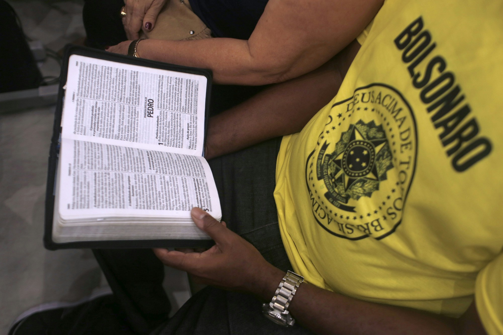 18 October 2018, Brazil, Rio de Janeiro: A man with a T-shirt with the inscription "Bolsonaro" reads the Bible during the last evangelical mass before the election in Brazil. Bolsonaro is receiving an additional boost from the evangelical movements in Brazil, which support his conservative agenda. Photo: Ian Cheibub/dpa (Photo by Ian Cheibub/picture alliance via Getty Images)