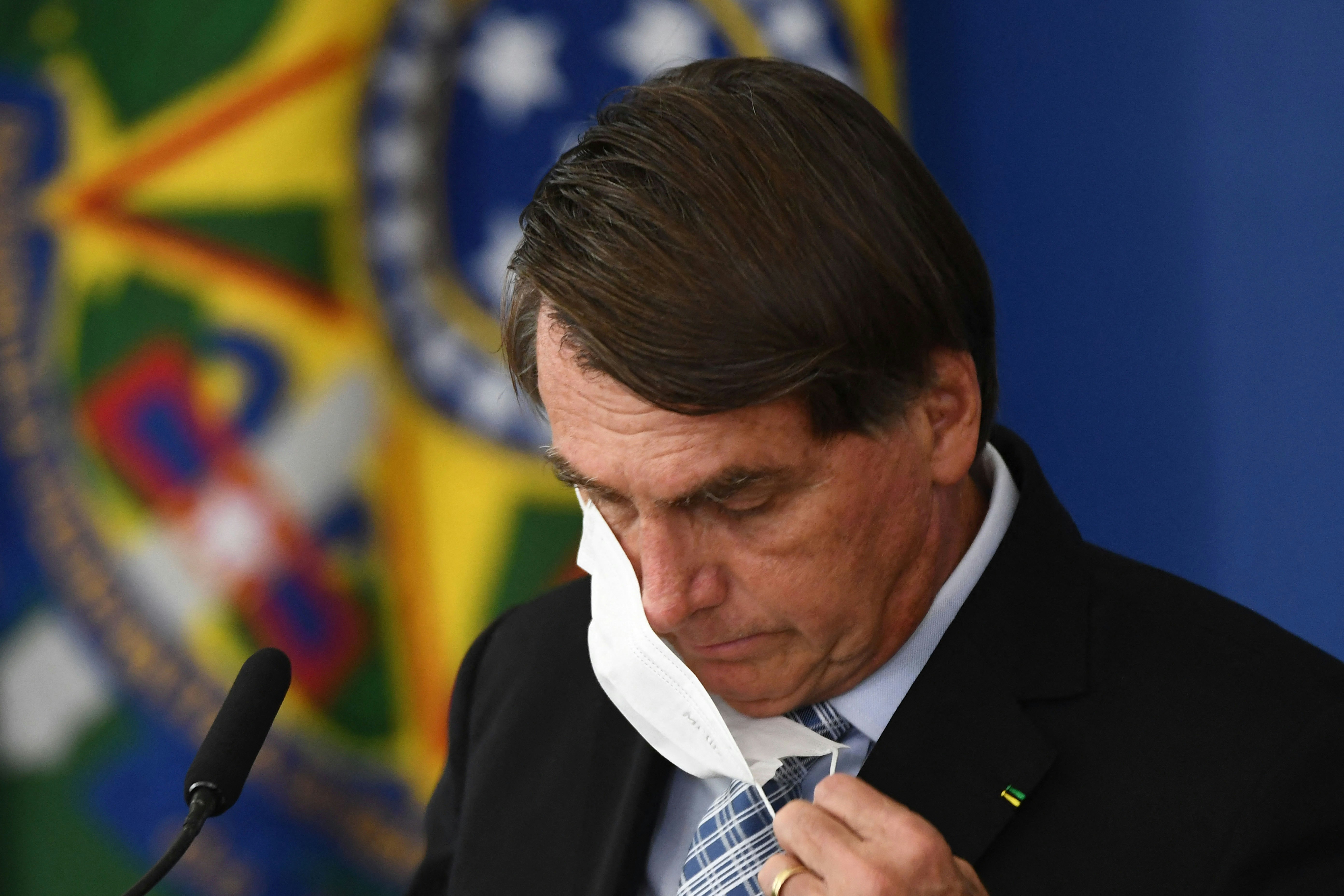 Brazilian President Jair Bolsonaro takes off his face mask before speaking during the sanction of the law that authorizes states, municipalities and the private sector to buy vaccines against COVID-19, at the Planalto Palace in Brasilia, on March 10, 2021. - Until now, with more than 260,000 deaths by the coronavirus, only the federal Government was authorized to buy vaccines. (Photo by EVARISTO SA / AFP) (Photo by EVARISTO SA/AFP via Getty Images)