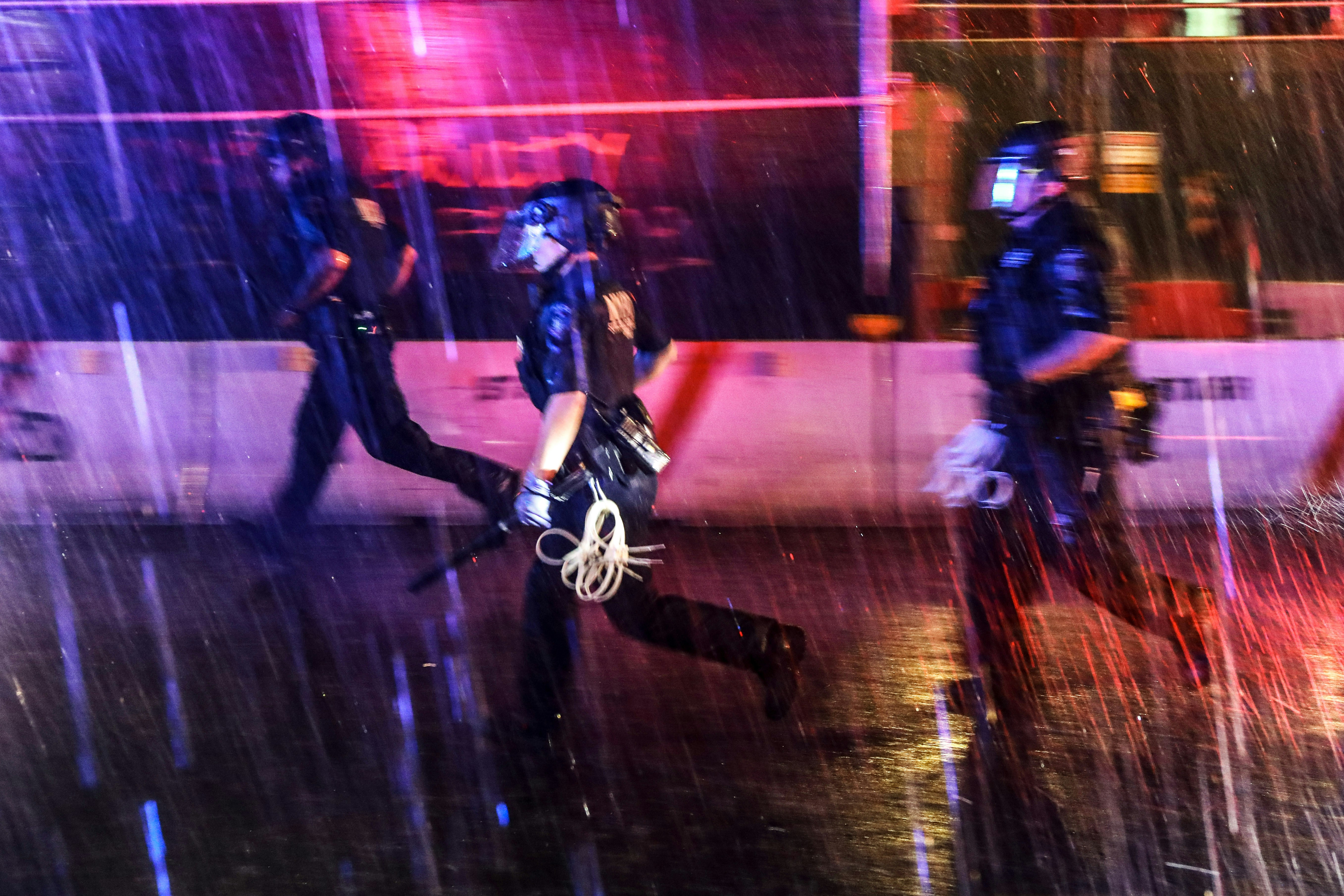 NEW YORK, NEW YORK - JUNE 03: Police chase after protesters in the rain as demonstrations continue in Manhattan over the killing of George Floyd by a Minneapolis Police officer on June 03, 2020 in New York City. The white police officer, Derek Chauvin, has been charged with second-degree murder and the three other officers who participated in the arrest have been charged with aiding and abetting second-degree murder. Floyd's death, the most recent in a series of deaths of African Americans at the hands of police, has set off days and nights of protests across the country.  (Photo by Spencer Platt/Getty Images)