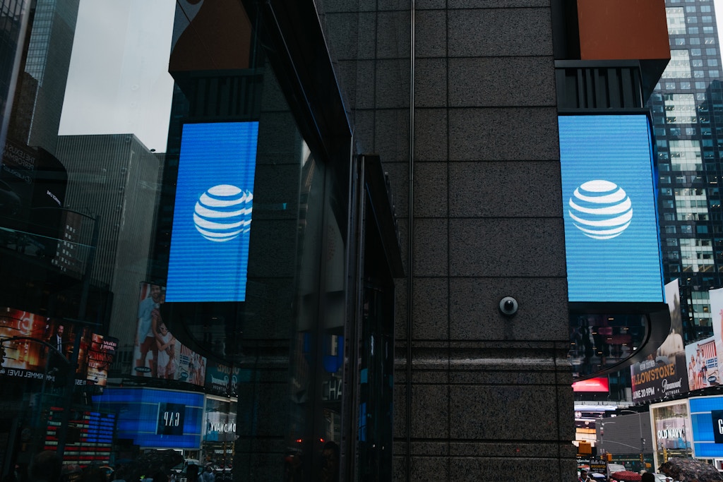An AT&T Inc. logo is reflected in a store window in New York, U.S., on Wednesday, June 13, 2018. AT&T Inc.'s sweeping court victory allowing its takeover of Time Warner Inc. delivers a sharp setback to the Justice Department's new approach to policing mergers under President Donald Trump and promises to spark a merger wave across industries. Photographer: Christopher Lee/Bloomberg via Getty Images
