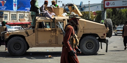 Taliban fighters stand guard in front of the Hamid Karzai International Airport, in Kabul, Afghanistan, Monday, Aug. 16, 2021. Thousands of people packed into the Afghan capital's airport on Monday, rushing the tarmac and pushing onto planes in desperate attempts to flee the country after the Taliban overthrew the Western-backed government. (AP Photo/Rahmat Gul)