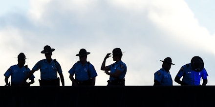 Police stand guard on a bridge as protestors block the road next to burned Wendy's restaurant on the fourth day following Rayshard Brooks' shooting death by police in the restaurant parking lot, June 16, 2020, in Atlanta, Georgia. - The fatal shooting of Brooks, a black man, by a white police officer in Atlanta has poured more fuel on the raging US debate over racism, prompting another round of street protests and the resignation of the southern city's police chief. The death of 27-year-old Rayshard Brooks was ruled a homicide by the county medical examiner's office on June 14, 2020, a day after the Wendy's restaurant where he died was set on fire and hundreds of people marched to denounce the killing. (Photo by CHANDAN KHANNA / AFP) (Photo by CHANDAN KHANNA/AFP via Getty Images)