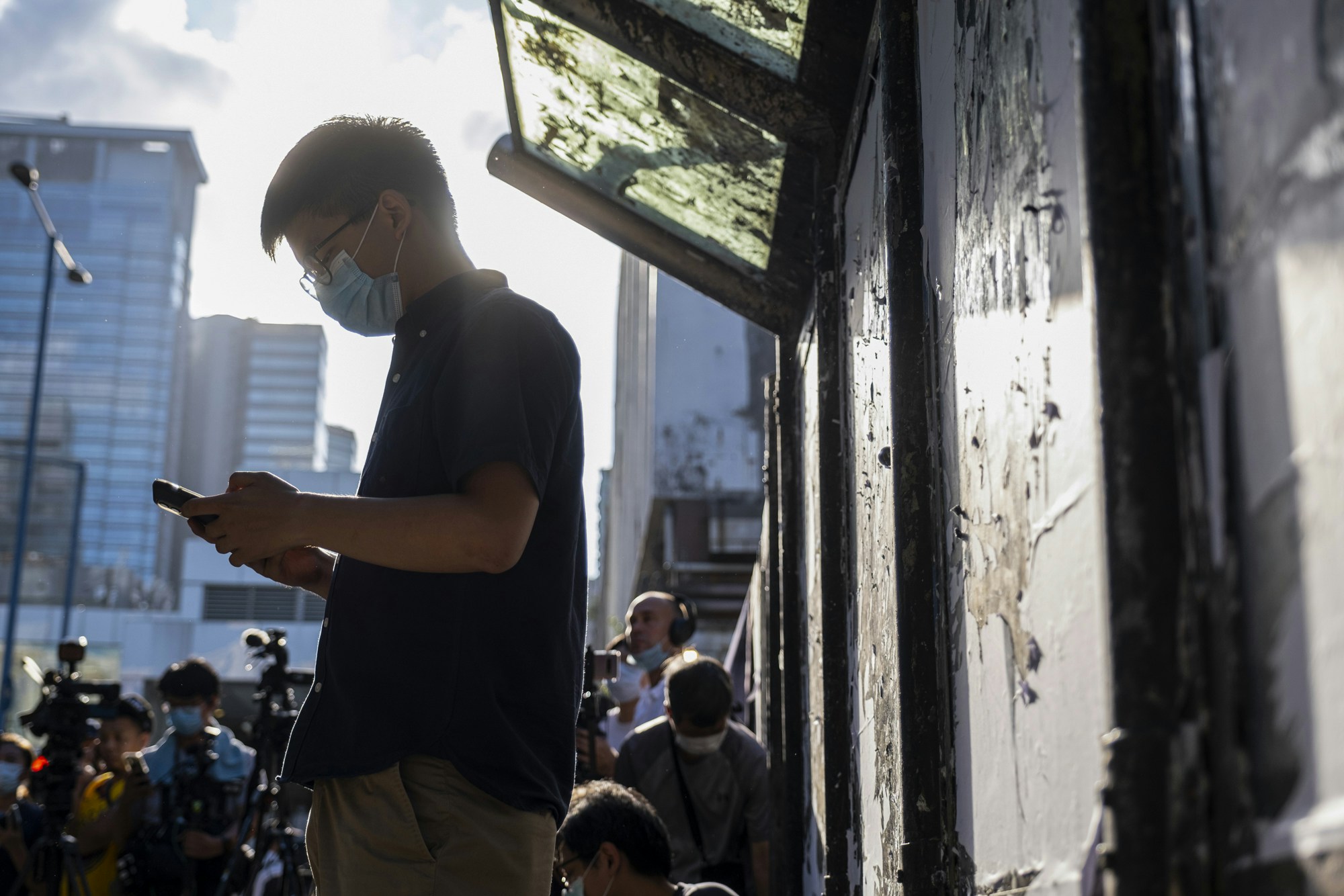 Joshua Wong, secretary-general of the Demosisto political party, wears a protective face mask as he uses his smart phone during a news conference to announce his bid to enter into the unofficial pro-democratic camp primary election for the Legislative Council in Hong Kong, China, on Friday, June 19, 2020. To overcome fractures between the moderates and more radical localists, legal scholar Benny Tai is attempting to organize an unofficial primary on July 11 and July 12 to select favored candidates in each district. Photographer: Chan Long Hei/Bloomberg via Getty Images