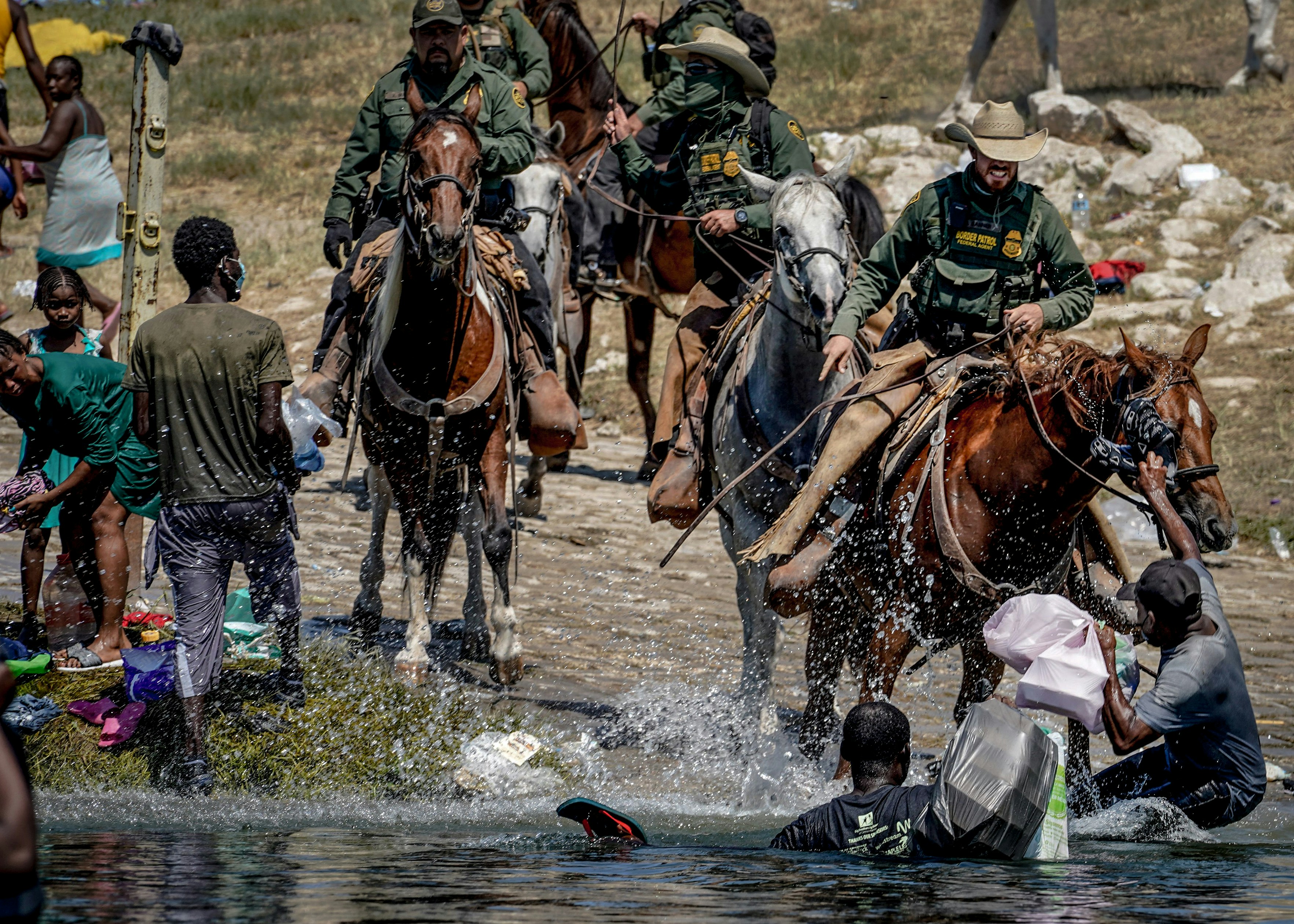 United States Border Patrol agents on horseback tries to stop Haitian migrants from entering an encampment on the banks of the Rio Grande near the Acuna Del Rio International Bridge in Del Rio, Texas on September 19, 2021. - The United States said Saturday it would ramp up deportation flights for thousands of migrants who flooded into the Texas border city of Del Rio, as authorities scramble to alleviate a burgeoning crisis for President Joe Biden's administration. (Photo by PAUL RATJE / AFP) (Photo by PAUL RATJE/AFP via Getty Images)