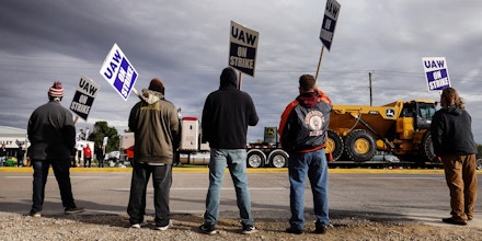 John Deere equipment passes workers picketing outside of the John Deere Davenport Works facility in Davenport, Iowa, on Oct. 15, 2021.