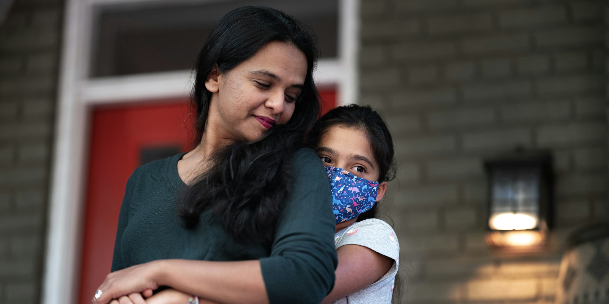 Kavitha Kasargod-Staub is embraced by her 10-year-old daughter on the front porch of their home in Washington, D.C., on October 19, 2021.