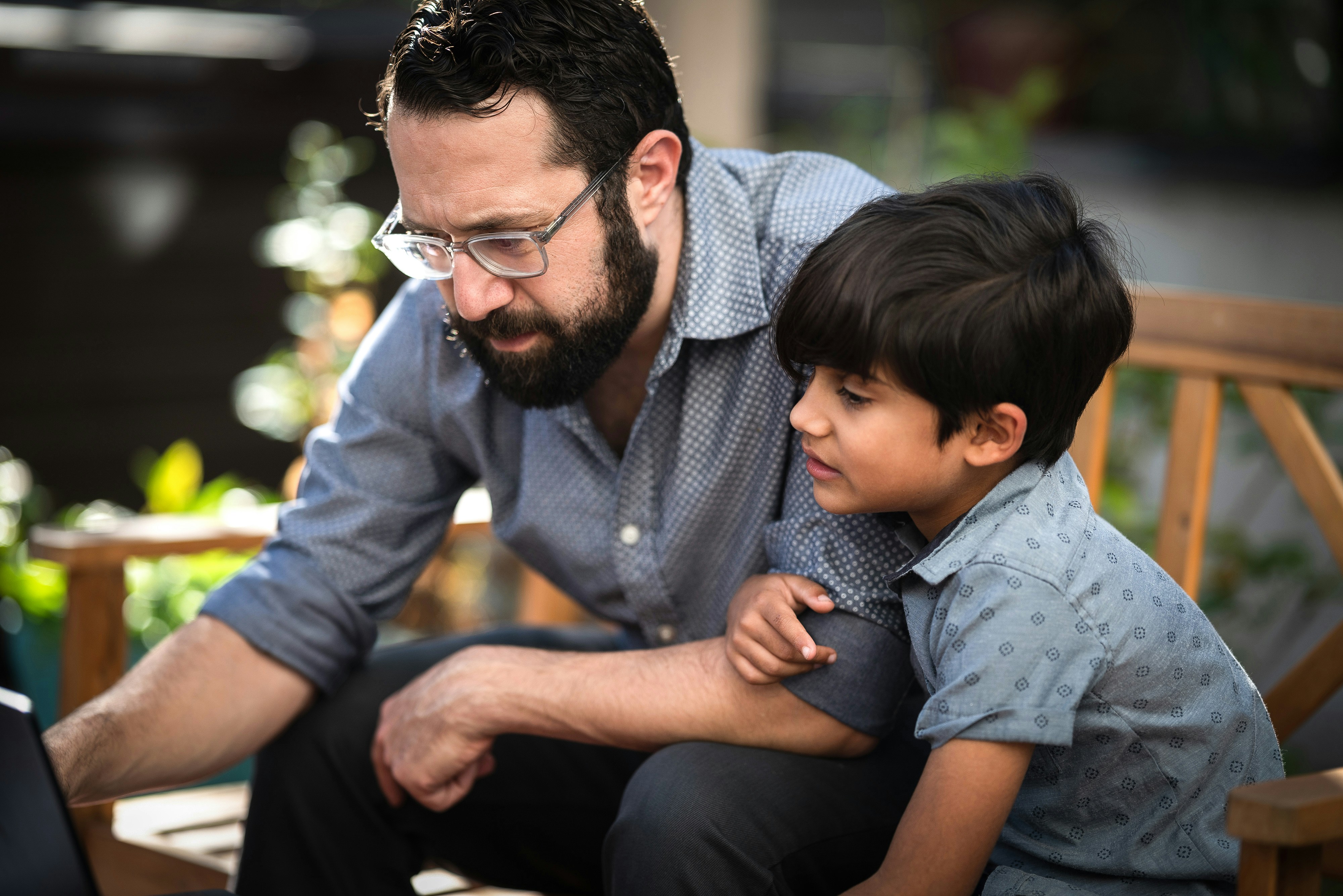 Eli Kasargod-Staub helps his seven-year-old son with his schoolwork, in the backyard of their home in Washington, D.C. on Tuesday, October 19, 2021. Photo by Cheriss May