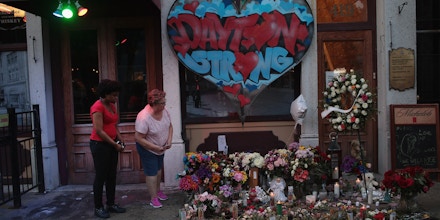 DAYTON, OHIO - AUGUST 06: People look over a memorial to those killed in Sunday morning's mass shooting while the businesses along E. 5th Street in the Oregon District try to return to normal on August 06, 2019 in Dayton, Ohio.  Nine people were killed and another 27 injured when a gunman identified as 24-year-old Connor Betts opened fire with a AR-15 style rifle in the popular entertainment district. Betts was subsequently shot and killed by police. The shooting happened less than 24 hours after a gunman in Texas opened fire at a shopping mall killing 22 people.  (Photo by Scott Olson/Getty Images)