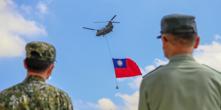 Taiwanese soldiers stand guard as a Chinook Helicopter carrying a tremendous Taiwan flag flies over a military camp, as part of a rehearsal for the flyby performance for Taiwans Double-Ten National Day Celebration, amid rising tensions between Beijing and Taipei and threats from China, in Taoyuan, Taiwan 28 September 2021. The 18-meter wide and 12-meter long Taiwan flag, according to state media Central News Agency, will be carried by two CH-47 Chinook helicopters flag flying over the Presidential Building on October 10, whilst the island has been developing better ties with the US, UK, Australia, and other European countries such as Lithuania, Czech Republic and Poland. (Photo by Ceng Shou Yi/NurPhoto via Getty Images)