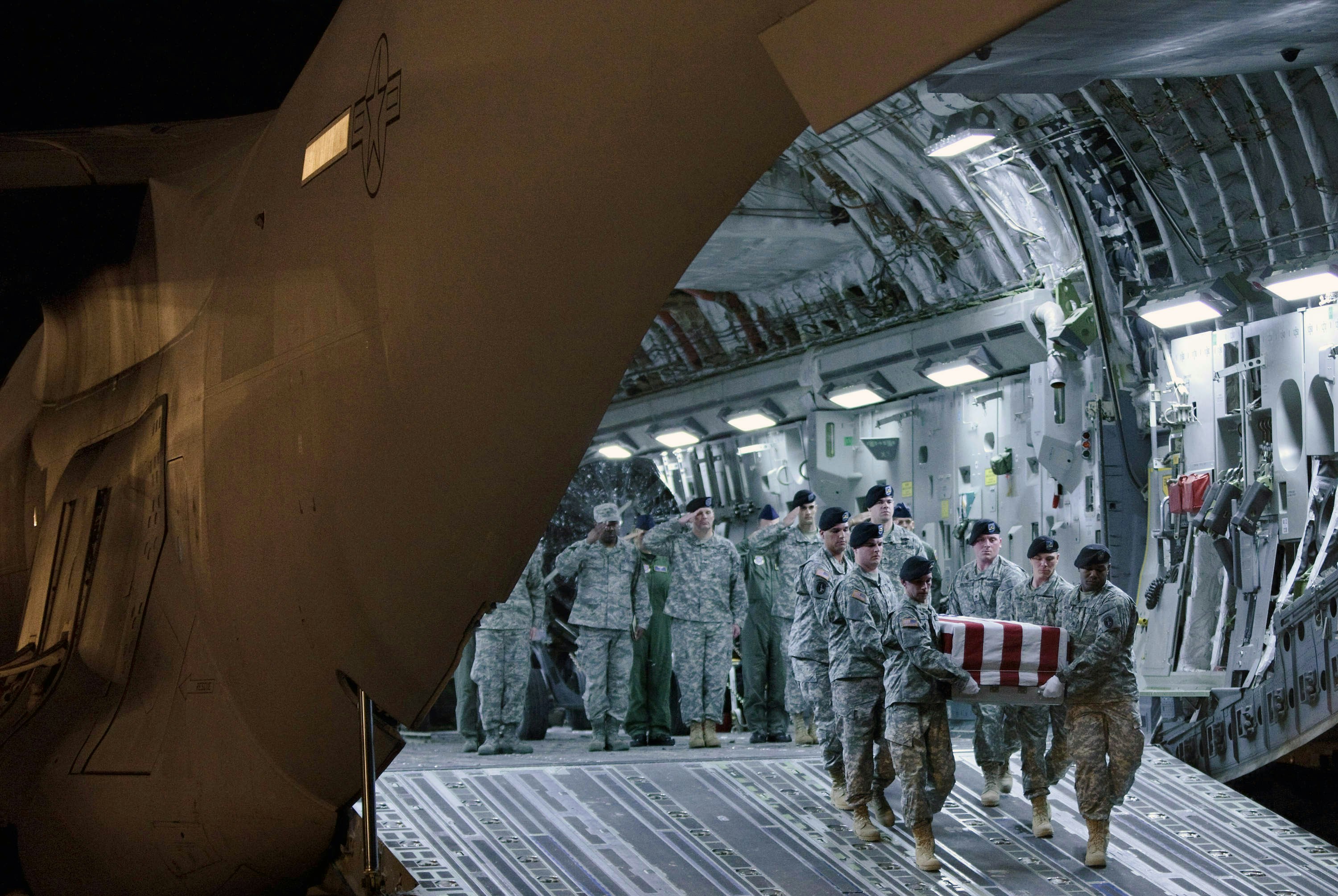 U.S. military personnel carry the casket containing the rema