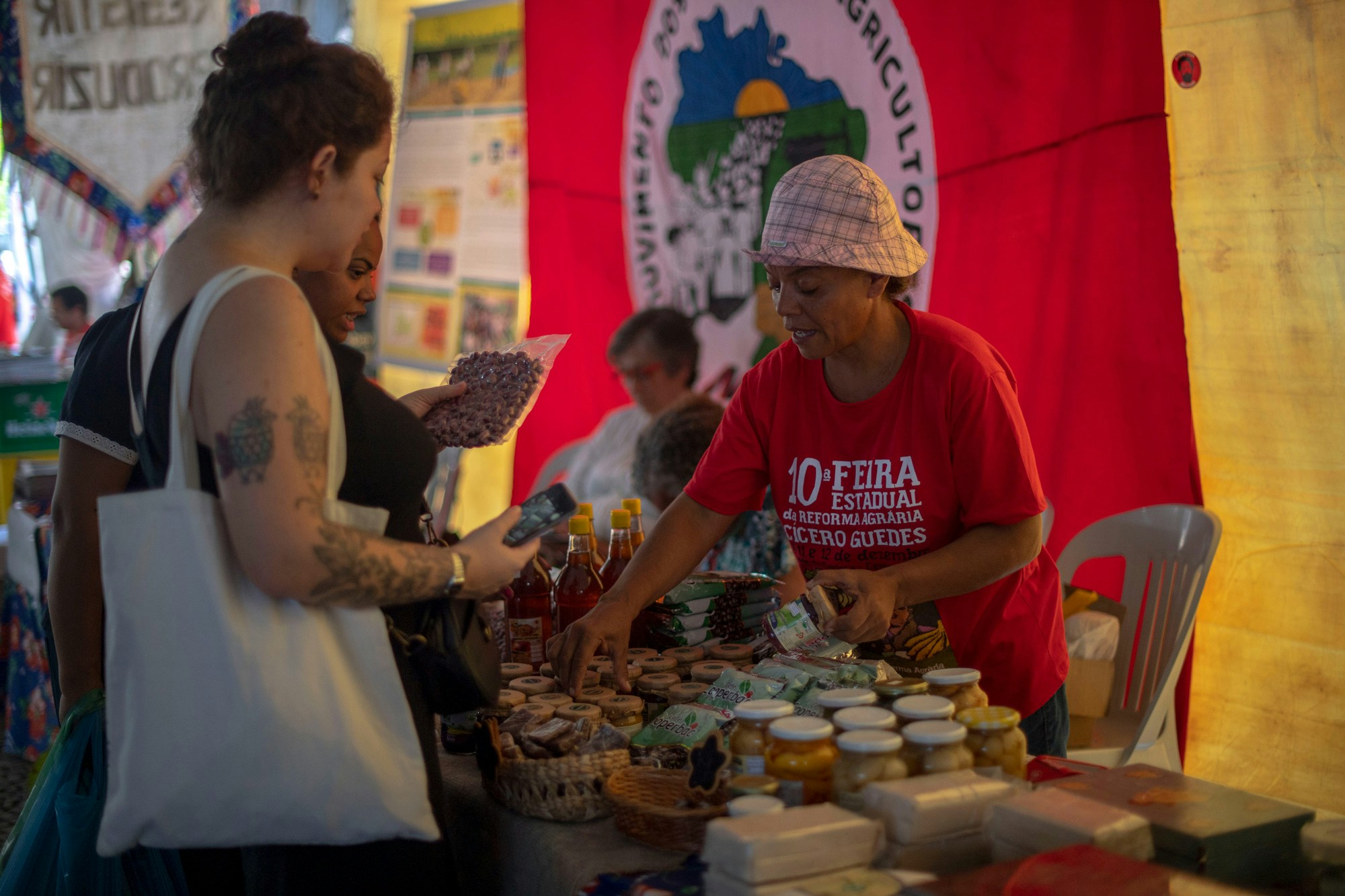 A member of the Landless Workers Movement (MST) sells products, made by MST members in the lands where they are settled, during the annual MST Fair at Carioca Square in downtown Rio de Janeiro, Brazil on December 12, 2018. - The Landless Workers Movement (MST), was born in 1984 and became one of the most important social organizations in Latin America, which since its origins has been claming for arable land for small farmers, defending an environmentally friendly agriculture, the opposite concept to the current model. The inauguration of Bolsonaro's far-right new government in January augurs even harder times for the Movement. (Photo by Mauro Pimentel / AFP)        (Photo credit should read MAURO PIMENTEL/AFP via Getty Images)
