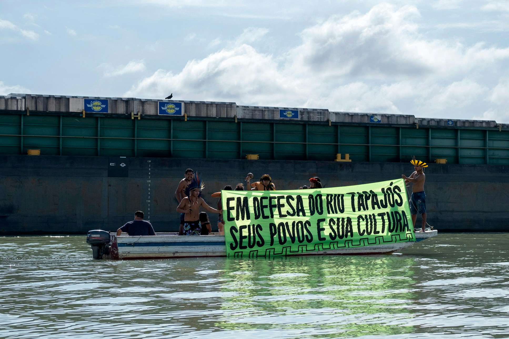 Indigenous protestors from the Tupinamba tribe display a banner reading In defense of the Tapajos river, its people and their culture during a protest over environmental concerns and land rights, on a boat on the Tapajos river, in Santarem, Para state, Brazil, on November 13, 2021. (Photo by Leondro MILANO / AFP) (Photo by LEONDRO MILANO/AFP via Getty Images)