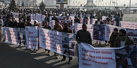 People hold banners before marching on the street during a protest in Kabul on December 21, 2021, as the country struggles with a deep economic crisis. (Photo by Mohd RASFAN / AFP) (Photo by MOHD RASFAN/AFP via Getty Images)