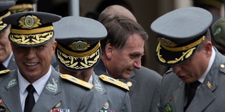 In this Dec. 1, 2018 photo, Brazil's President-elect Jair Bolsonaro walks past Brazilian Army generals during a graduation ceremony at the Agulhas Negras Military Academy in Resende, Brazil.  Bolsonaro, who waxes nostalgic for Brazil's 1964-1985 military dictatorship, makes no bones about his debt to the academy, which he graduated from in 1977. (AP Photo/Leo Correa)