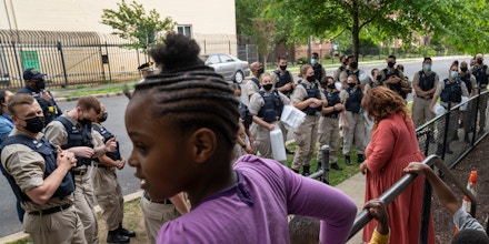 WASHINGTON DC - MAY 14 DC Kahliou Settle, 8, left, watches Metro Police trainees during a tour by neighborhood activists and residents in the Woodlawn Terrace area on May 14, 2021 in Washington, DC. The tours, where rookie officers meet with the community, are designed to give them a better understanding of the city and its culture. (Photo by Michael Robinson Chavez/The Washington Post via Getty Images)