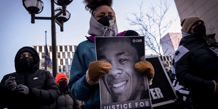 A demonstrator holds a photo of Amir Locke during a rally in protest of his killing, outside the Hennepin County Government Center in Minneapolis, Minnesota on February 5, 2022. - Authorities in the US city of Minneapolis, where George Floyd was murdered in 2020, published body-cam video on February 3 showing the police shooting of a 22-year-old African American man. According to the police, Amir Locke was shot on Wednesday by officers who were executing a search warrant on the apartment he was in, after Locke pulled a gun from beneath a blanket. (Photo by Kerem Yucel / AFP) (Photo by KEREM YUCEL/AFP via Getty Images)