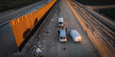 YUMA, ARIZONA - DECEMBER 11: In an aerial view, U.S. Border Patrol agents receive immigrants after they walked through a gap in the wall from Mexico on December 11, 2021 in Yuma, Arizona. They had made the arduous journey from Brazil and Chile in South America. Yuma has seen a surge of migrant crossings in the past week, with many immigrants trying to reach U.S. soil before the court-ordered re-implementation of the Trump-era Remain in Mexico policy. The policy requires asylum seekers to stay in Mexico during their U.S. immigration court process. (Photo by John Moore/Getty Images)
