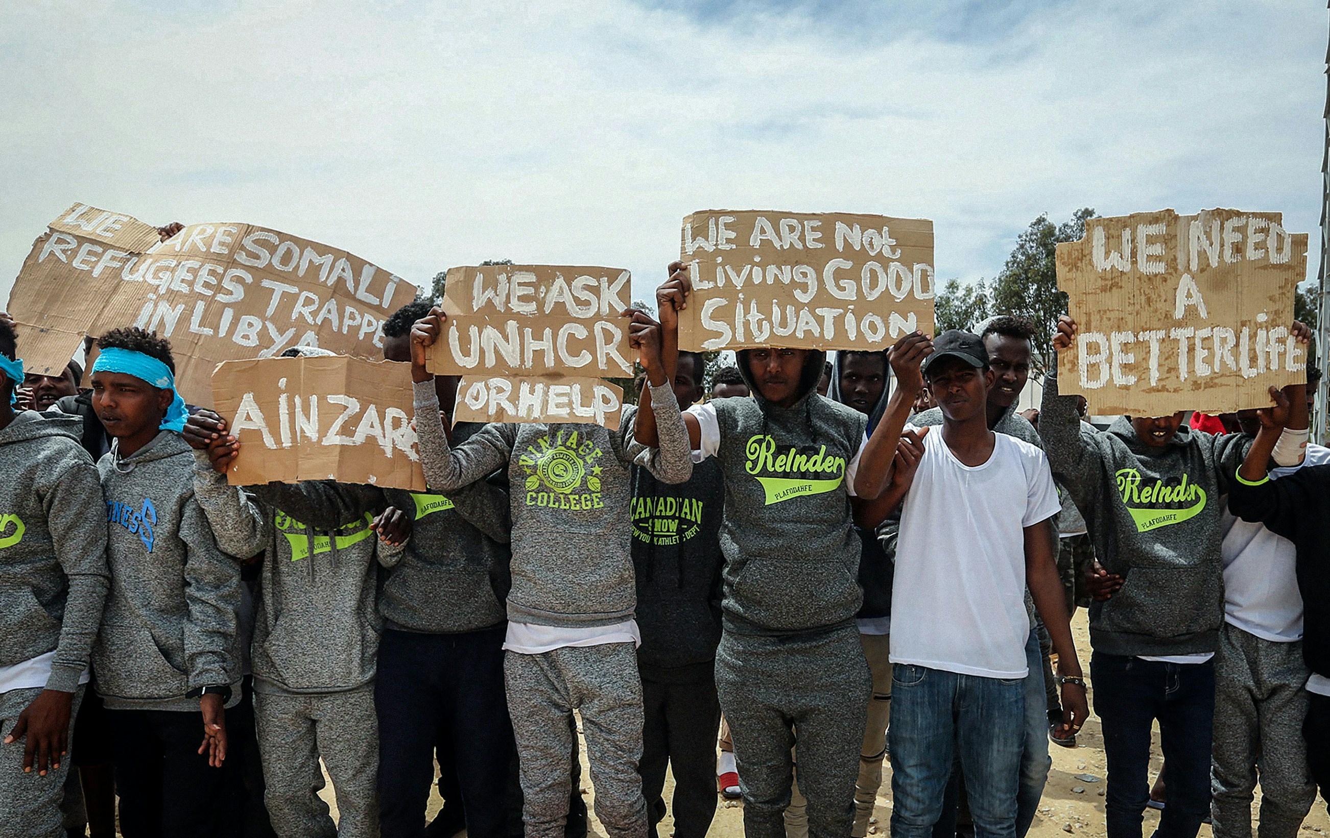 Migrants hold placards during United Nations Secretary-General Antonio Guterres (unseen) visit to Ain Zara detention centre for migrants in the Libyan capital Tripoli on April 4, 2019. -  (Photo by Mahmud TURKIA / AFP)        (Photo credit should read MAHMUD TURKIA/AFP via Getty Images)
