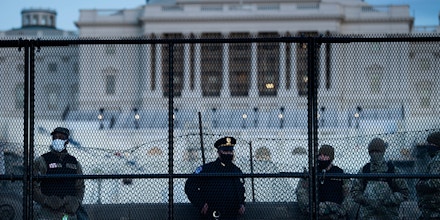 A Capitol Police officer stands with members of the National Guard behind a crowd control fence surrounding Capitol Hill a day after a pro-Trump mob broke into the US Capitol on January 7, 2021