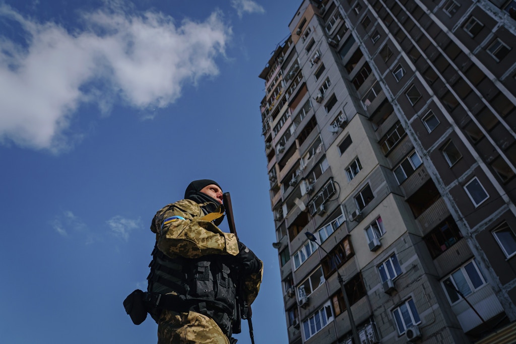 KYIV, UKRAINE -- MARCH 17, 2022: A soldier stands guard outside a damaged residential building caused by what authorities say is an intercepted missile that fell from the sky in the Pozniaky neighborhood of Kyiv, Ukraine, Thursday, March 17, 2022. (MARCUS YAM / LOS ANGELES TIMES)