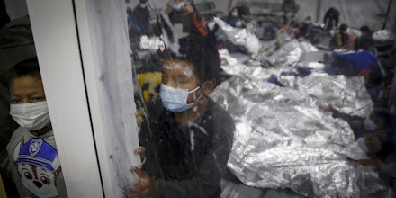 Young children look out from inside a pod at the Donna Department of Homeland Security holding facility, the main detention center for unaccompanied children in the Rio Grande Valley run by the Customs and Border Patrol (CBP), in Donna, Texas on March 30, 2021. - The children are housed by the hundreds in eight pods that are about 3,200 square feet in size. Many of the pods had more than 500 children in them. The Biden administration on Tuesday for the first time allowed journalists inside its main detention facility at the border for migrant children, revealing a severely overcrowded tent structure where more than 4,000 kids and families were crammed into pods and the youngest kept in a large play pen with mats on the floor for sleeping. (Photo by Dario Lopez-Mills / POOL / AFP) (Photo by DARIO LOPEZ-MILLS/POOL/AFP via Getty Images)