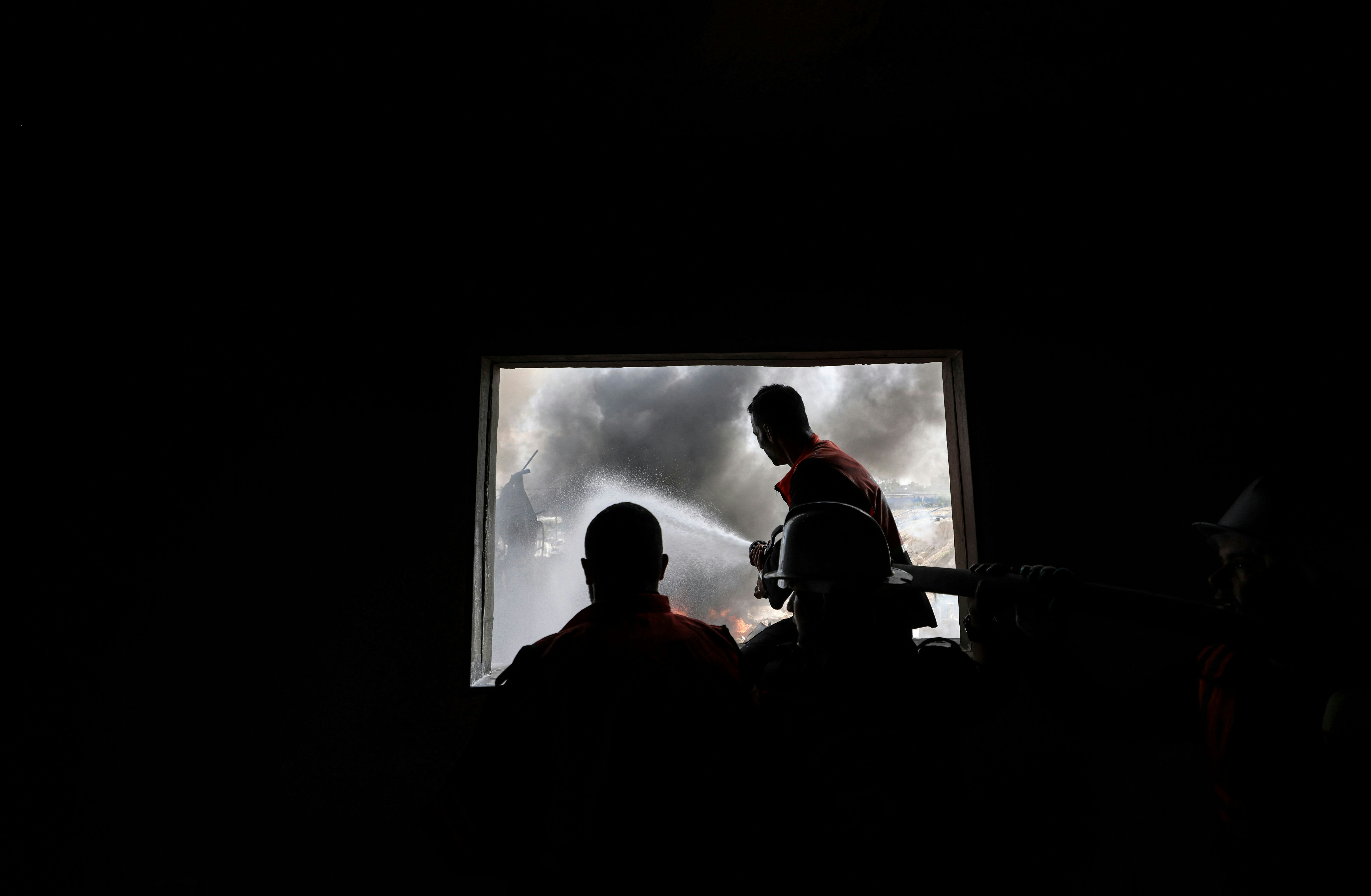 Des pompiers palestiniens éteignent un énorme incendie dans l'usine de matelas Foamco à l'est de Jabalia, dans le nord de la bande de Gaza, le 17 mai 2021. (Photo de MAHMUD HAMS / AFP) (Photo de MAHMUD HAMS/AFP via Getty Images)