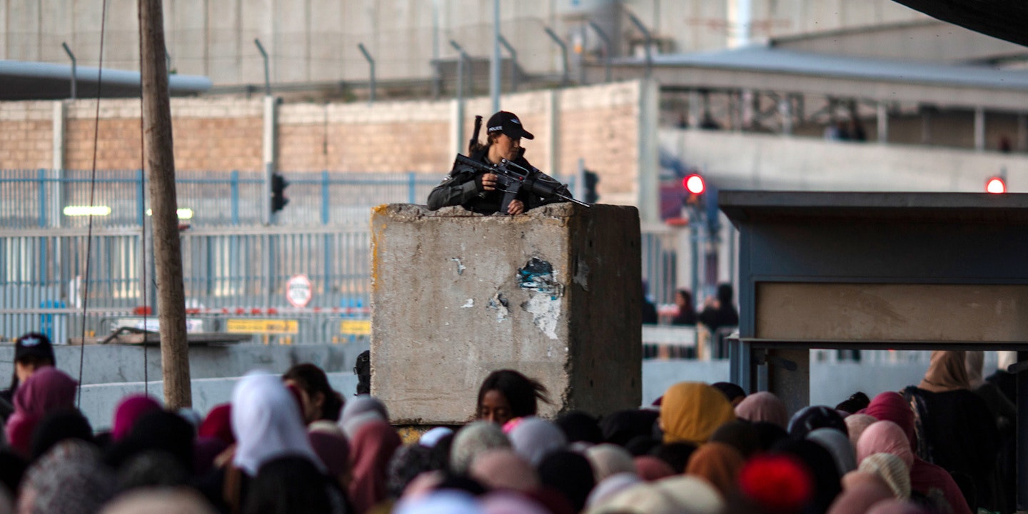 An Israeli border police stands guard as Palestinians make their way through Qalandia checkpoint to attend the last Friday prayer of the holy fasting month of Ramadan in Al-Aqsa mosque, Palestinian Territories, Ramallah, April 29, 2022.