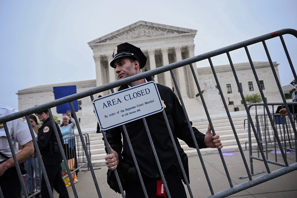 A police officer carries a barricade reading "area closed" as demonstrators gather in front of the US Supreme Court in Washington, DC, on May 3, 2022. - The Supreme Court is poised to strike down the right to abortion in the US, according to a leaked draft of a majority opinion that would shred nearly 50 years of constitutional protections. The draft, obtained by Politico, was written by Justice Samuel Alito, and has been circulated inside the conservative-dominated court, the news outlet reported. Politico stressed that the document it obtained is a draft and opinions could change. The court is expected to issue a decision by June. The draft opinion calls the landmark 1973 Roe v Wade decision "egregiously wrong from the start." (Photo by Brendan SMIALOWSKI / AFP) (Photo by BRENDAN SMIALOWSKI/AFP via Getty Images)
