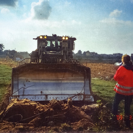 Rachel Corrie stands in front of an Israeli bulldozer to protest the destruction of Palestinian homes along the Rafah-Egypt border on March 16, 2003. Corrie was killed later the same day.