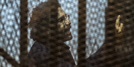 Egyptian activist and blogger Alaa Abdel Fattah gestures from behind the defendant's cage during his trial for insulting the judiciary alongside 25 other defendants including ousted Egyptian president Mohamed Morsi, who was recently sentenced to death, in Cairo on May 23, 2015. AFP PHOTO / KHALED DESOUKI        (Photo credit should read KHALED DESOUKI/AFP via Getty Images)