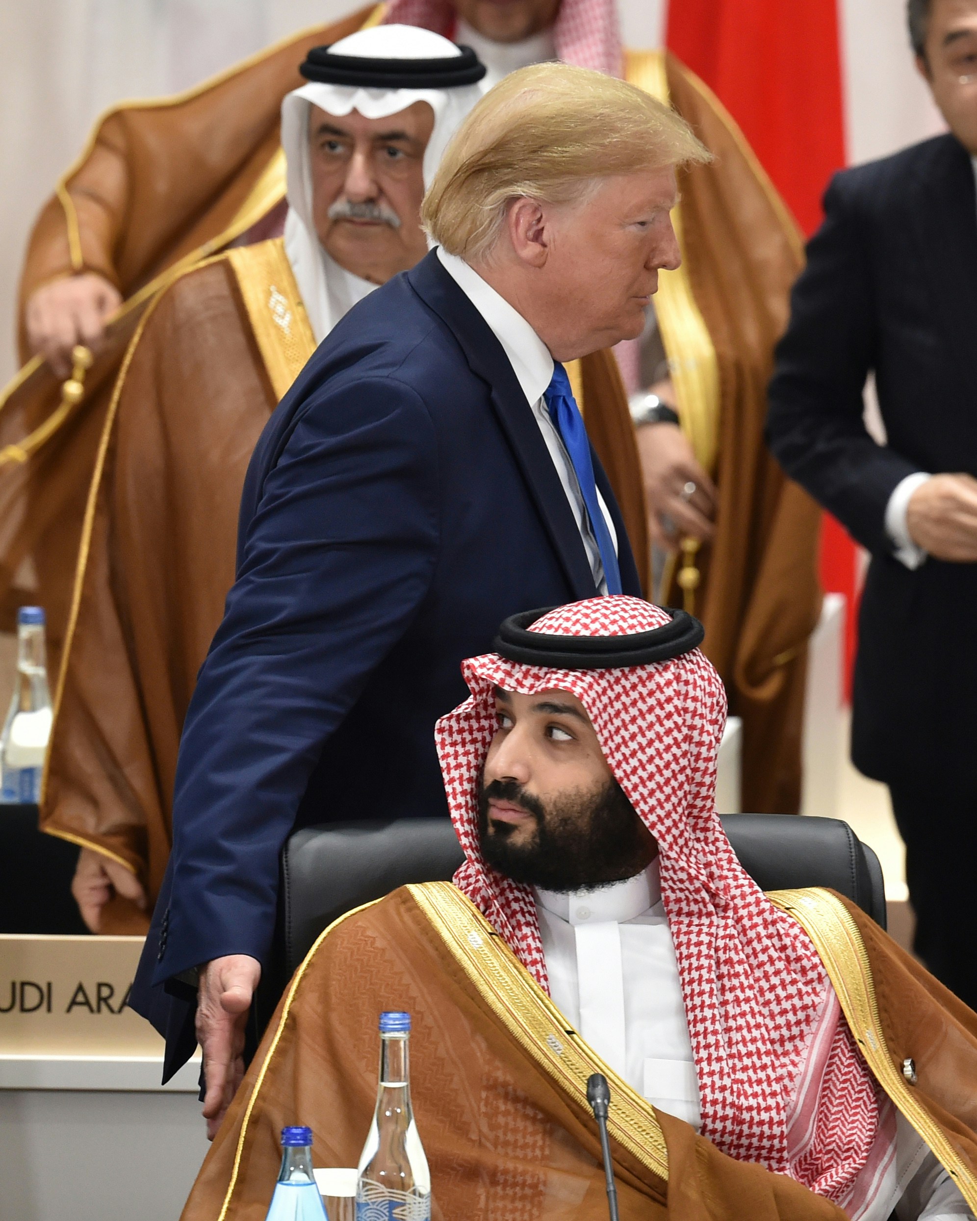 U.S. President Donald Trump, top, walks past Mohammed Bin Salman, Saudi Arabia's crown prince, bottom, as he arrives for a session at the Group of 20 (G-20) summit in Osaka, Japan, on Saturday, June 29, 2019. Disputes over wording on climate change and trade are unresolved shortly before Group of 20 leaders are due to release a communique from their summit in Japan, raising the risk of a very watered-down document or no statement at all. Photographer: Kazuhiro Nogi/Pool via Bloomberg