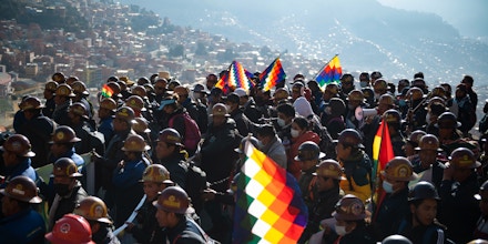 25 August 2022, Bolivia, La Paz: Supporters of President Arce's government march with flags and mining helmets during a rally in support of the government. 