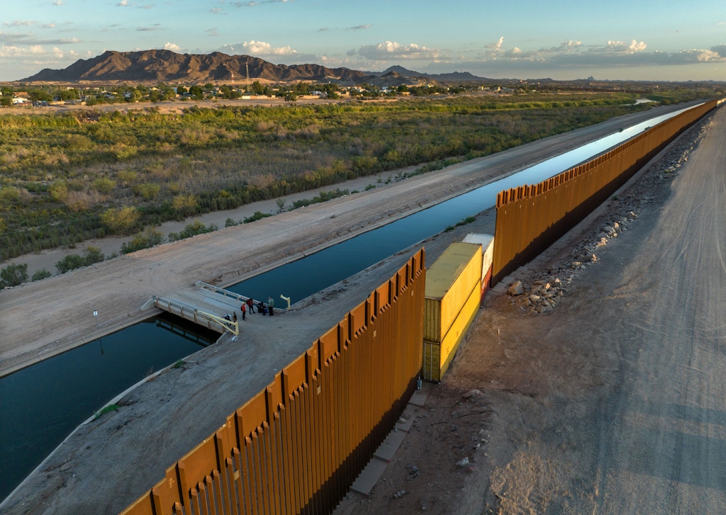 YUMA, ARIZONA - SEPTEMBER 27: In this aerial view, Cuban immigrants seeking asylum in the United States await transport by the U.S. Border Patrol after they crossed into Arizona from Mexico on September 27, 2022 in Yuma, Arizona. Some gaps in the border fence built by the Trump Administration were recently filled with shipping containers by the Arizona state government, making it more difficult for immigrants to cross in certain areas. The number of immigrants crossing into the U.S. in 2022 is set to be the highest in recent history, surpassing the historic highs of 2021. (Photo by John Moore/Getty Images)