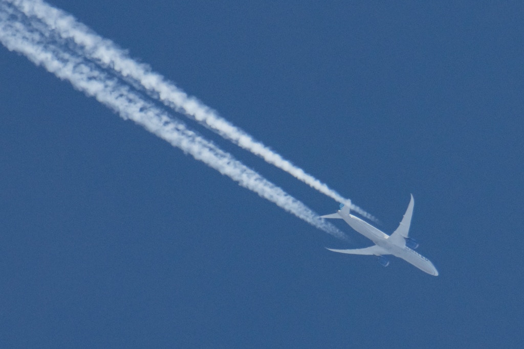 A United Airlines Boeing 787 Dreamliner airplane is seen overflying in the blue sky over Amsterdam. The wide-body aircraft is a B787-10 with registration N14011 flying transatlantic from Frankfurt FRA Germany to New York Newark EWR USA. The plane is flying at 36.000 feet forming contrails known as chemtrails also, condensation or vapor white lines, trails made in high altitude. . The world aviation passenger traffic numbers declined due to the travel restrictions, safety measures such as lockdowns, quarantine etc during the era of the Covid-19 Coronavirus pandemic that hit hard the aviation and travel industry. Amsterdam, Netherlands on April 1, 2021 (Photo by Nicolas Economou/NurPhoto via Getty Images)