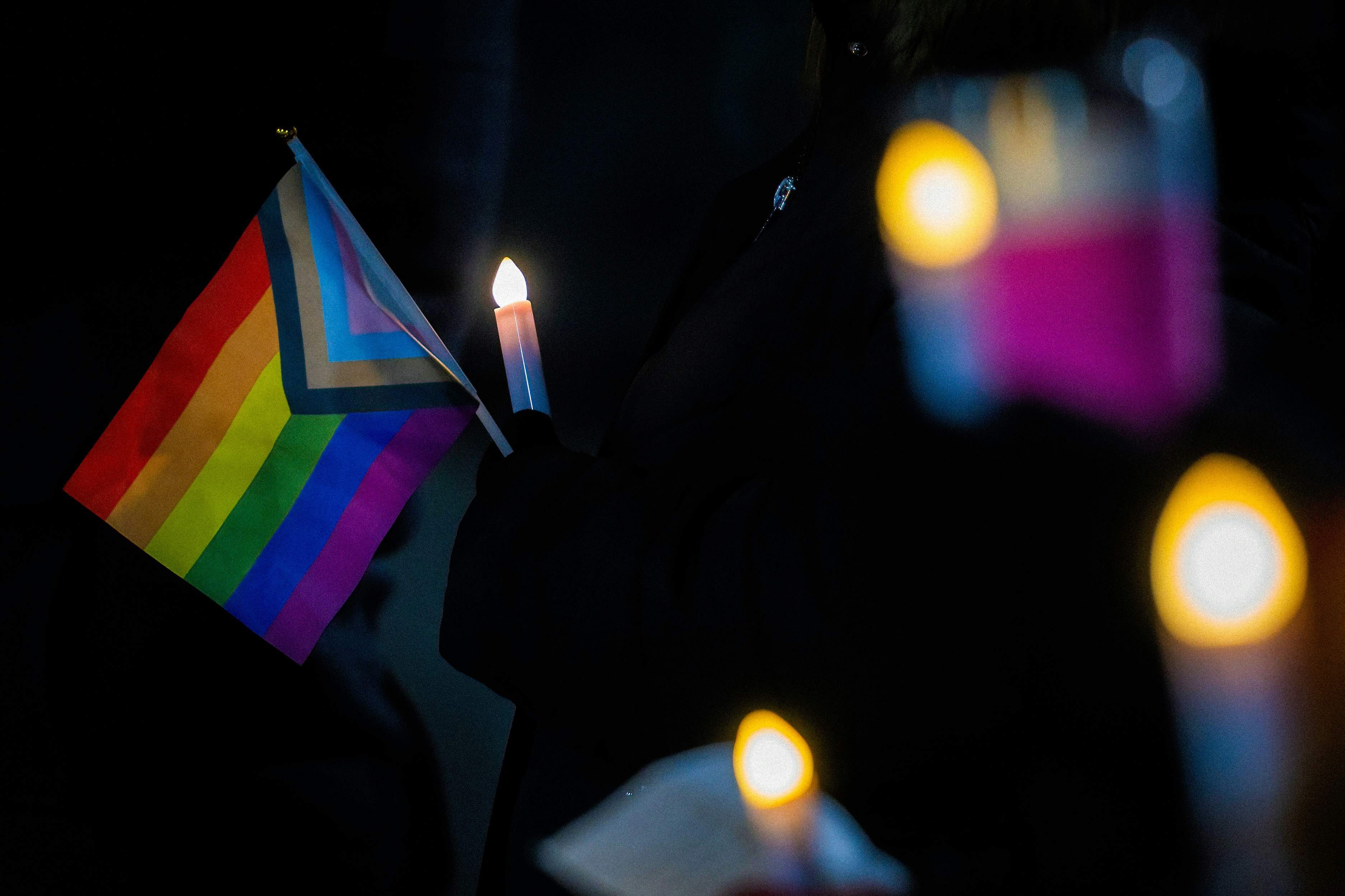 WILKES-BARRE, PENNSYLVANIA, UNITED STATES - 2022/11/20: A woman holds a Pride flag as others hold candles during the vigil. A crowd gathered at the Public Square for a Transgender Day of Remembrance Sunday evening. The vigil was to bring light to the rights of transgender people after a shooting at a gay club in Colorado. (Photo by Aimee Dilger/SOPA Images/LightRocket via Getty Images)