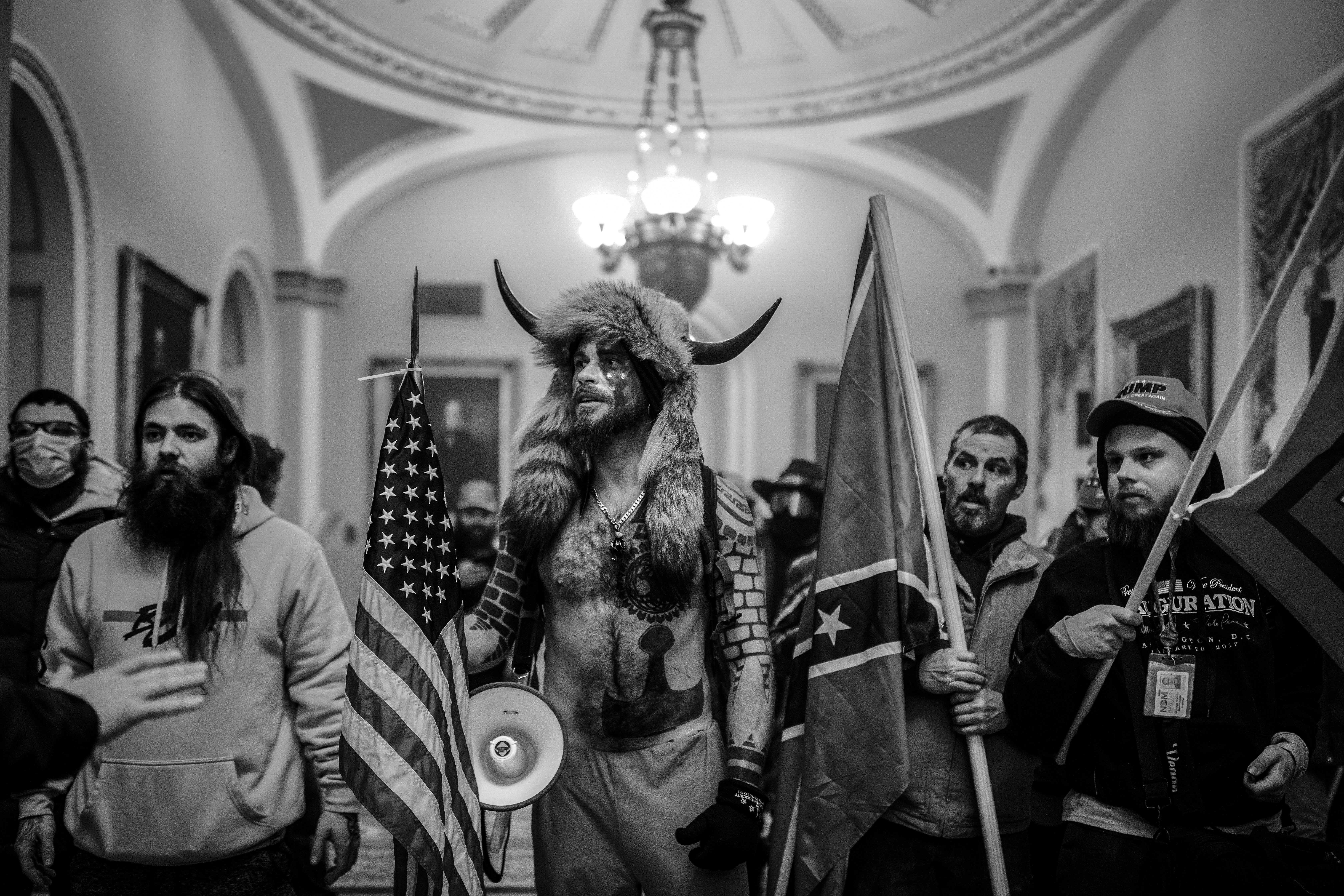 Jake Angeli, self described QAnon Shamen, confronts police officers as a pro-Trump mob storms the Capitol in Washington, D.C. after listening to a speech by President Trump on January 6, 2021. A large mob who convened on Washington, D.C. for a ?Save America? or ?Stop the Steal? rally was incited by President Trump and stormed the United States Capitol building, fighting with police, and damaging offices and rooms as they made their way through the building. As President Trump openly condoned the violence, the D.C, mayor called for a 6 p.m. curfew, and mobilized the National Guard. (Photo by Ashley Gilbertson / VII Photo)