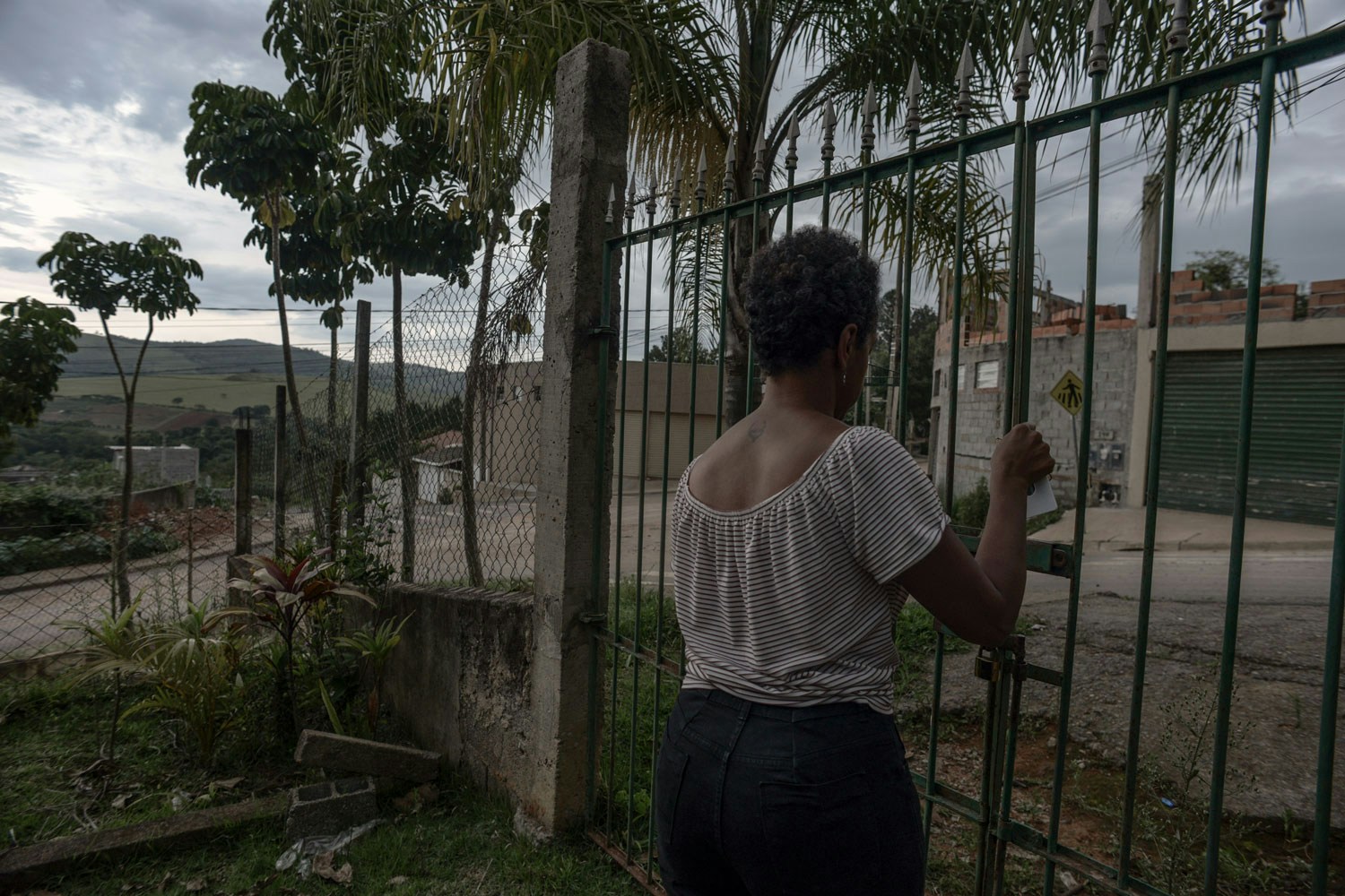 Mariana fechando o portão de sua antiga casa, na época das intimidações, em novembro de 2022.